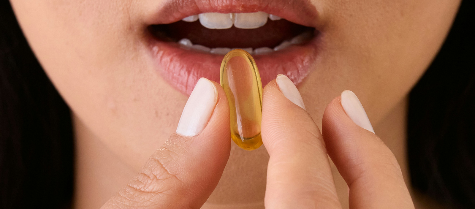 Person holding a gel capsule up to their mouth