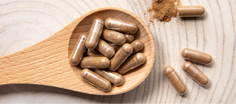 Powder capsules on a wooden spooon.